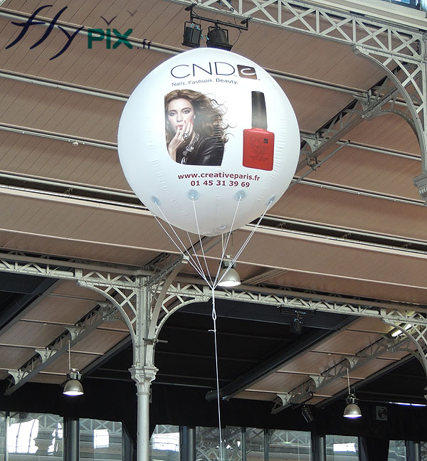 Ballon publicitaire à hélium gonflé avec du gaz hélium volant au dessus d'un stand.