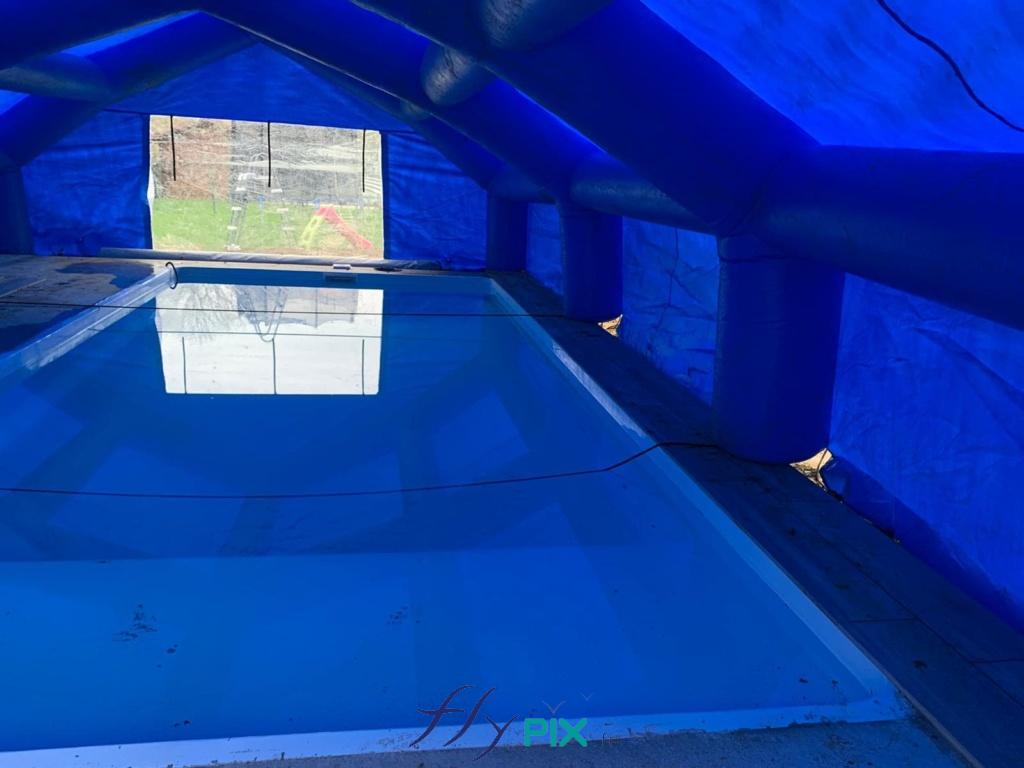 Vue intérieure d'une tente gonflable de chantier piscine, forme maison chapiteau, air captif, enveloppe PVC, pour travaux pose liner et maçonnerie.