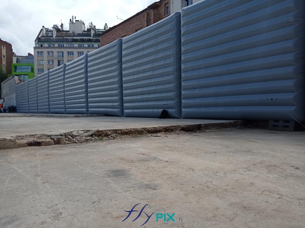 Des segments de murs gonflables, air captif, de dimensions 5 x 5 m, disposé en longueur, pour protéger les riverains et les habitants des nuisances sonores induites par les travaux de terrassement, BTP, forages ou démolition.